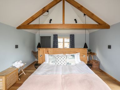A bedroom with a bed pillows and blankets under a wooden beam at Rynys in Llanddeiniolen near Llanrug