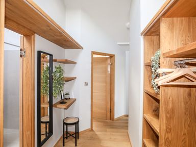 A hallway with wooden shelves hangers a mirror and a stool at Rynys in Llanddeiniolen near Llanrug