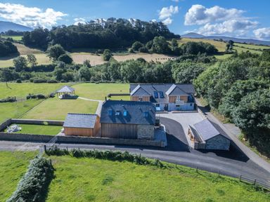 A countryside property with multiple buildings a gazebo and lawns surrounded by hills at Rynys in Llanddeiniolen near Llanrug