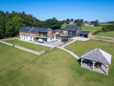 A large modern house with a detached garage and pavilion in a spacious grassy yard at Rynys in Llanddeiniolen near Llanrug