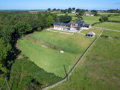 An aerial view of a house with a large fenced lawn and a gazebo in a rural area at Rynys in Llanddeiniolen near Llanrug