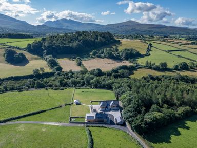 A rural property with houses and a gazebo surrounded by fields and trees at Rynys in Llanddeiniolen near Llanrug