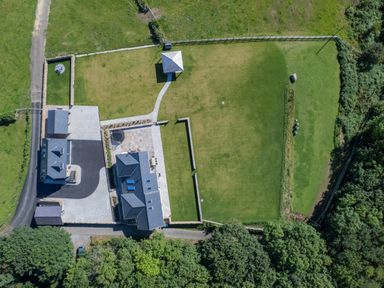 Aerial view of a property with two buildings a gazebo a paved patio and large grassy area at Rynys in Llanddeiniolen near Llanrug