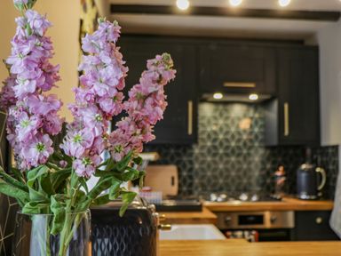A kitchen with pink flowers in a vase on a wooden countertop at April Cottage in Whitby