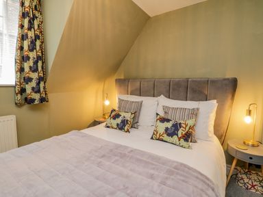 A bedroom with a bed with cushions and bedside tables with lamps at April Cottage in Whitby