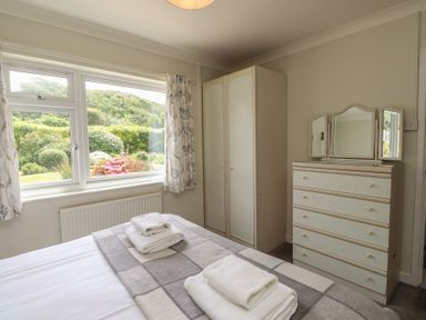 A bedroom with a bed, wardrobe, and dressing table at Bro Mebyd, Criccieth