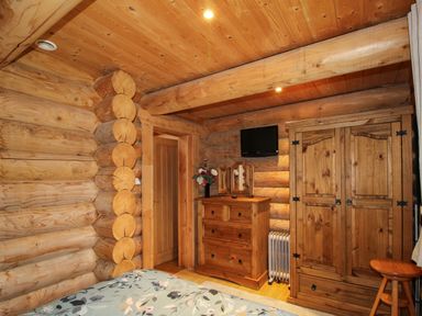A wooden bedroom with a dresser mirror wardrobe TV and a bed at Brynallt Country Park Frankton near Ellesmere