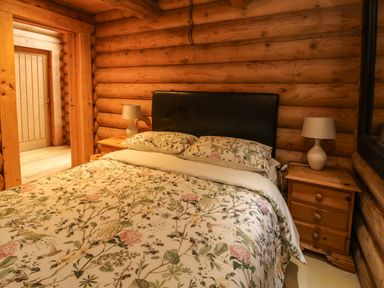 A bedroom with a bed and floral bedding between two wooden nightstands with lamps at Brynallt Country Park Frankton near Ellesmere