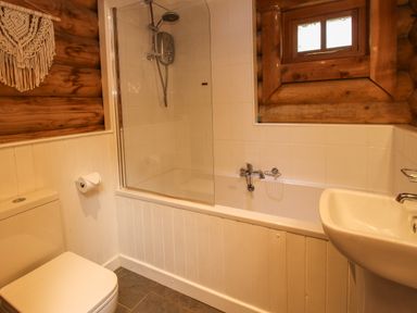 A bathroom with a toilet sink bathtub shower and wooden window frame at Brynallt Country Park Frankton near Ellesmere