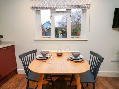 A dining table set for two with chairs near a window with blinds at Llygad Y Dydd in Bow Street Wales