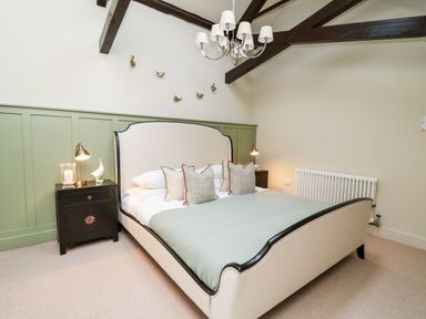 A bedroom with a bed green panel wall bedside tables and wall-mounted lights at Llygad Y Dydd in Bow Street Wales