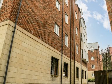 An exterior view of a brick and stone building with multiple windows and downpipes at Estuary Walk in Whitby