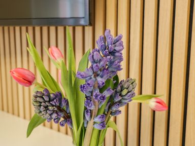 A vase with purple and pink flowers on a white surface in front of a wooden slatted wall at Estuary Walk Whitby