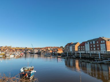 A harbor with boats docked and buildings along the water at Estuary Walk in Whitby
