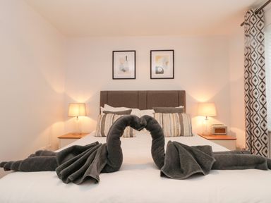 A bedroom with a bed with towel swans on it and bedside tables with lamps at Estuary Walk in Whitby