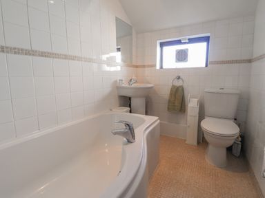 A bathroom with a bathtub sink toilet and a window at Hillcrest in Oxwich near Port Eynon