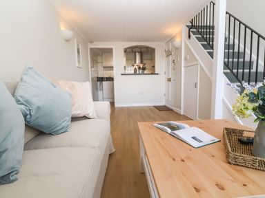 A living room with sofa cushions a wooden coffee table flowers and stairs at 58 High Street in Falmouth
