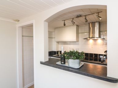 A kitchen with a countertop holding a tray with a bottle and a plant at 58 High Street in Falmouth