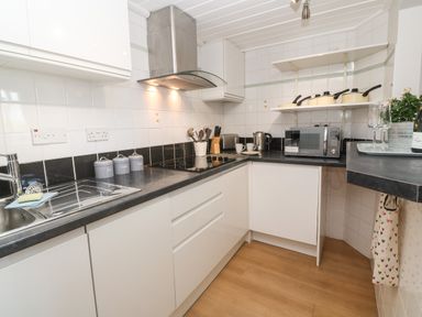 A kitchen with white cabinets black countertops a stovetop a microwave and kitchen utensils at 58 High Street in Falmouth
