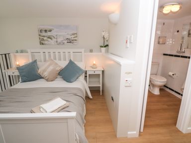 A bedroom with a white bed and pillows next to a bathroom with a toilet at 58 High Street in Falmouth