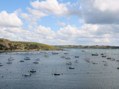 A harbor with multiple sailboats and motorboats anchored near a coastline with green hills at 58 High Street in Falmouth
