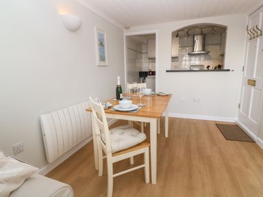 A dining room with a wooden table set for four and a view into a kitchen at 58 High Street in Falmouth