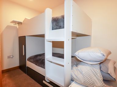 A bedroom with white bunk beds and pillows at Clonmore in Bodmin