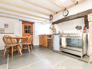 A kitchen with wooden dining table and chairs a stainless steel oven and wooden cabinets at Trelash Cottage in Trelash near Boscastle