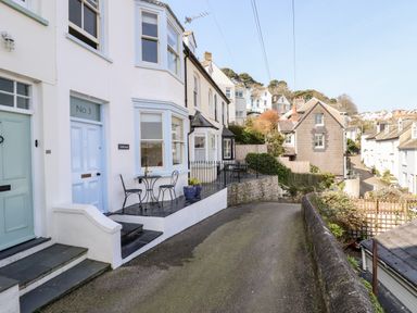 A row of houses along a narrow curved street with outdoor seating areas at Driftwood in Fowey