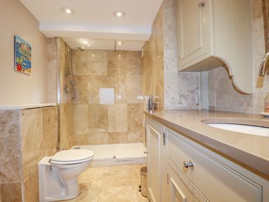 A bathroom with a toilet shower and countertop with sink at Driftwood in Fowey