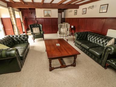A living room with green leather sofas wooden coffee table and armchairs at The Granary in Longhirst near Morpeth
