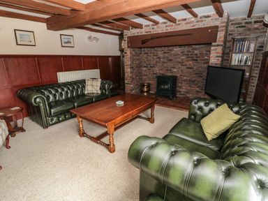 A living room with two green leather sofas a wooden coffee table and a brick fireplace at The Granary in Longhirst near Morpeth