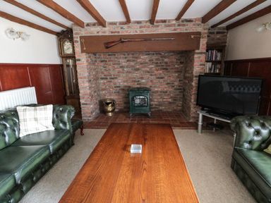 A living room with green leather sofas a wooden coffee table a TV and a brick fireplace at The Granary in Longhirst near Morpeth