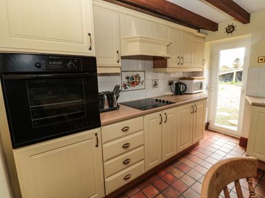 A kitchen with built in oven stove microwave kettle and toaster with cream cabinets and tiled floor at The Granary in Longhirst near Morpeth