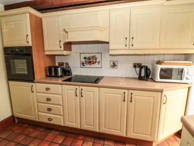 A kitchen with cream cabinets countertop oven toaster microwave and kettle at The Granary in Longhirst near Morpeth