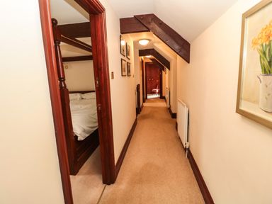 A carpeted hallway with a radiator on the right wall and a partially visible bedroom on the left at The Granary in Longhirst near Morpeth
