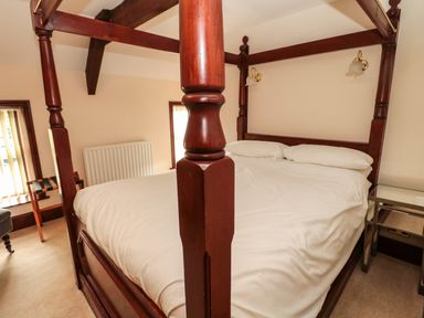A bedroom with a four-poster bed white bedding windows and bedside tables at The Granary in Longhirst near Morpeth