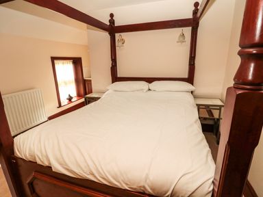 A bedroom with a wooden canopy bed with white bedding and pillows at The Granary in Longhirst near Morpeth