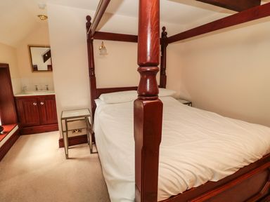 A bedroom with a four-poster bed a bedside table and a sink area at The Granary in Longhirst near Morpeth