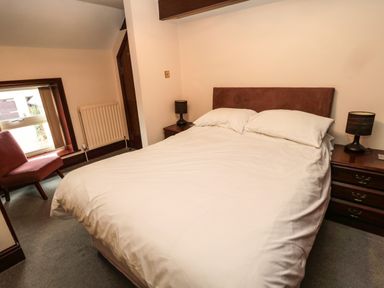 A bedroom with a bed a chair two bedside tables and lamps at The Granary in Longhirst near Morpeth