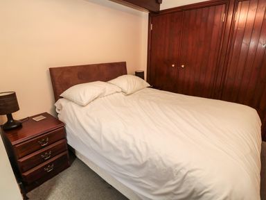 A bedroom with a bed white bedding bedside tables and wooden wardrobes at The Granary in Longhirst near Morpeth