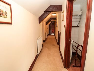 A narrow hallway with beige carpet and wooden beams at The Granary in Longhirst near Morpeth