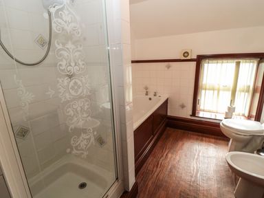 A bathroom with a shower, bathtub, toilet, bidet, and window with blinds at The Granary in Longhirst near Morpeth
