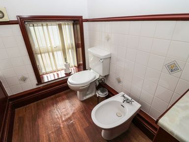 A bathroom with a toilet, bidet, and window with vertical blinds at The Granary in Longhirst near Morpeth