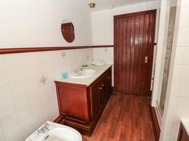 A bathroom with a sink vanity tiled walls a wooden door and a bidet at The Granary in Longhirst near Morpeth