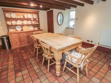 A dining room with a wooden table and six chairs a wooden dresser with plates and cups on display at The Granary in Longhirst near Morpeth