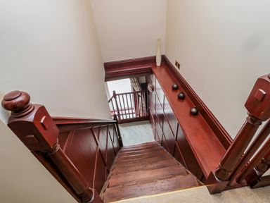 A wooden staircase with brown paneling and small decorative vases on the ledge at The Granary in Longhirst near Morpeth