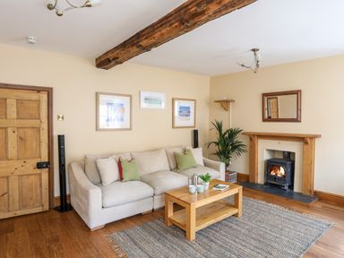 A living room with a beige sofa a wooden coffee table a rug and a fireplace at Above Deck in Beaumaris