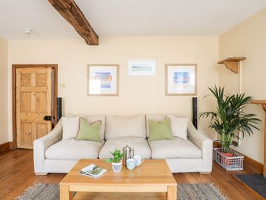 A living room with a beige sofa green cushions wooden coffee table and framed pictures on the wall at Above Deck in Beaumaris