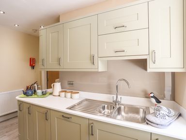 A kitchen countertop with a double sink cabinets and a tray with teapot and cups at Above Deck in Beaumaris